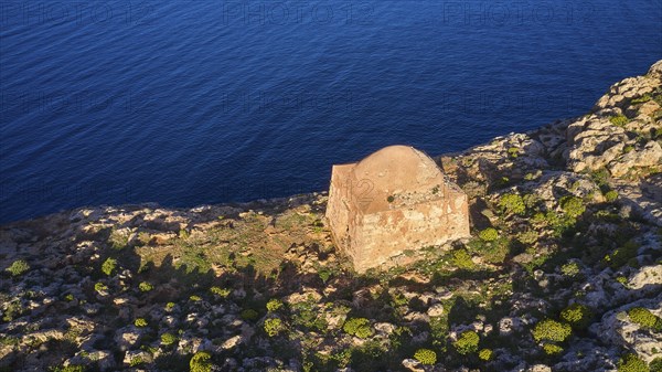 Drone shot, A single ruin on a rocky cliff above the blue sea, surrounded by vegetation, square defence defence tower with dome, Venetian sea fortress, Gramvoussa, Gramvoussa peninsula, Pirate Bay, Balos, lagoon, Northwest Crete, Crete, Greek Islands, Greece, Europe