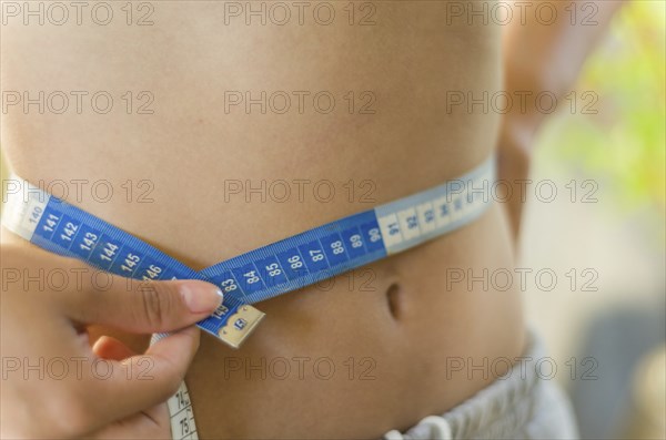 Skinny young woman measuring her slim waist with a measuring tape