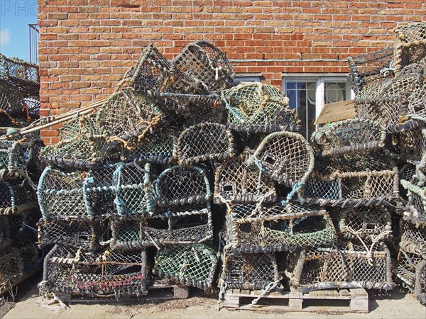 Lobster pots used in traditional fishing for crustaceans stacked against a building in scarborough harbour