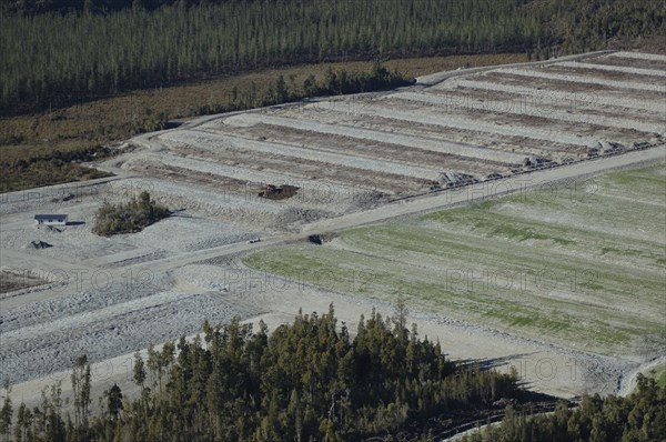 Digger excavating land to make humps and hollows for farmland, West Coast, South Island, New Zealand. Humping and hollowing is an effective way of draining swampy land for dairy pasture