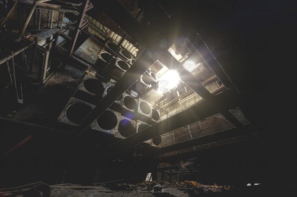 A dark interior of an industrial plant with rays of light shining through the roof, Metallwerke Bender, Lost Place, Linn, Krefeld, North Rhine-Westphalia, Germany, Europe