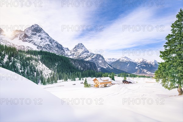 Rustic scenery with wooden houses surrounded by the snowy Alps mountains, the green fir forests and a thick layer of snow, in Ehrwald, Austria, Europe