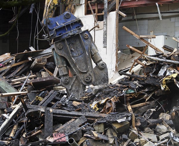 A demolition shear working on dismantling a destroyed house