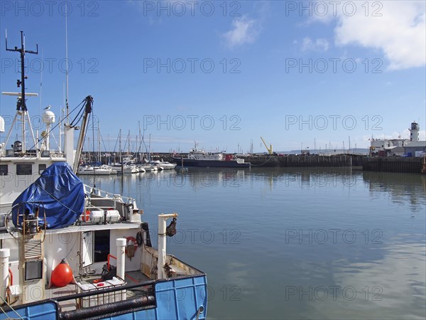 Trawler and leisure boats moored in Scarborough harbour and marina in summer sunlight