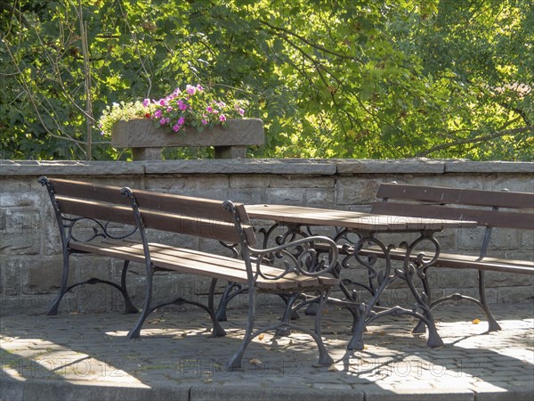 Park benches and a table next to a stone wall with flowers, on a sunny day, krudenburg, hünxe, lower rhine, germany