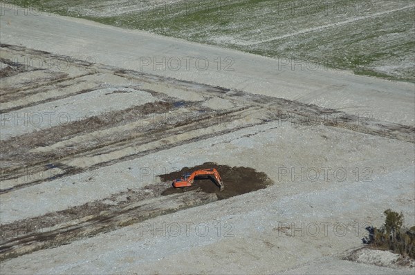 Digger excavating land to make humps and hollows for farmland, West Coast, South Island, New Zealand. Humping and hollowing is an effective way of draining swampy land for dairy pasture