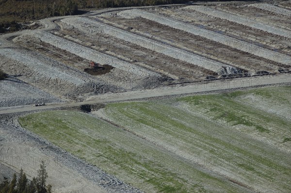 Diggers excavating land to make humps and hollows for farmland, West Coast, South Island, New Zealand. Humping and hollowing is an effective way of draining swampy land for dairy pasture