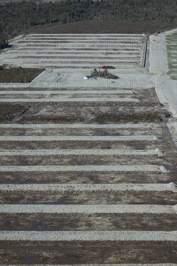 Digger excavating land to make humps and hollows for farmland, West Coast, South Island, New Zealand. Humping and hollowing is an effective way of draining swampy land for dairy pasture