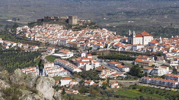 Woman viewing Castelo de Vide from a rock in Alentejo, Portugal from Serra de Sao Mamede mountains