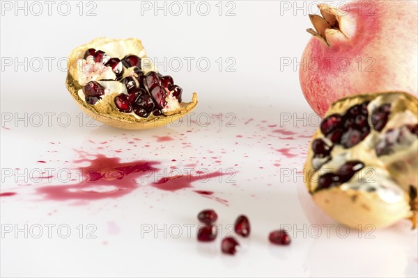 Half pomegranate and seeds on white background