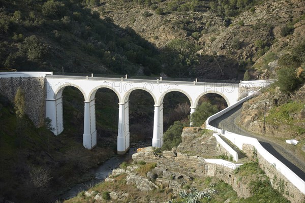 Mertola beautiful white and stone bridge on the city entrance with almond trees on the landscape in Alentejo, Portugal, Europe