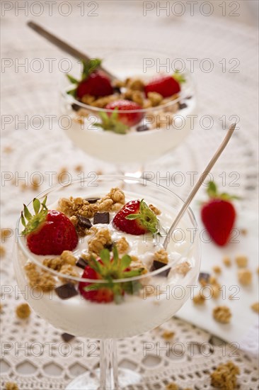 Dessert with strawberries cereals and chocolate flakes inside a cup with plain yogurt