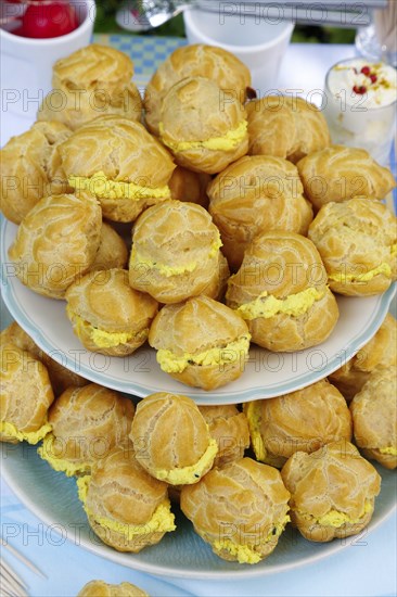 Swabian cuisine, mini cream puffs filled with goat's cream cheese, cream cheese éclairs, profiterole arranged on plate, shortbread, oven cakes, choux pastry, pastry, hearty, salty, choux pastry, baked, from the oven, vegetarian, bake, from the oven, typical Swabian reinterpreted, party pastry, finger food, appetisers for on the go, traditional cuisine reinterpreted, food photography, Germany, Europe