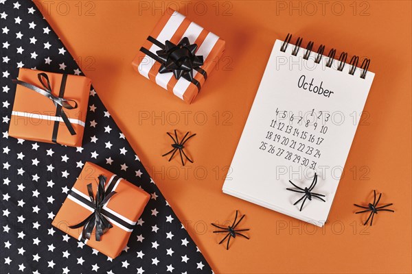 Calendar sheet for month October with Halloween spiders and gift boxes on orange and black background with star fabric