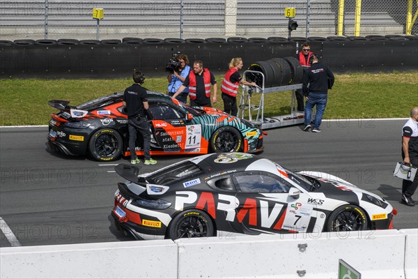 Team manager of car racing team and mechanic with spare tyres next to racing car Sports car Porsche Cayman GT4 Clubsport preparing for the start of car racing, in the foreground Porsche Cayman GT4, racing series GTC Racing GT Sprint, ADAC Racing Weekend, TT Circuit Assen, Assen, province Drenthe, Netherlands