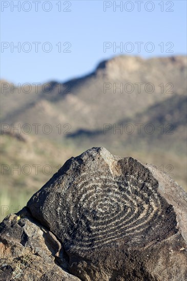 Rock art at Signal Hill, created by the Hohokam Indians, showing spiral petroglyph with the Tucson Mountains in the background, Saguaro National Park, Arizona, US