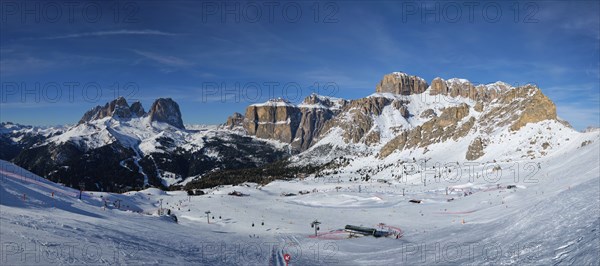 Panorama of a ski resort piste with people skiing in Dolomites in Italy. Ski area Belvedere. Canazei, Italy, Europe