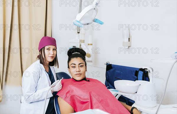 Portrait of young dentist with female patient in medical office, Female dentist with female patient looking at camera, Professional dentist with female patient in office