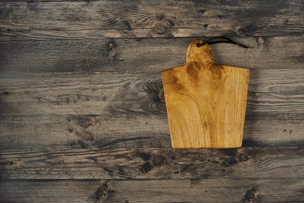 A beautifully crafted wooden cutting board rests on a rustic wooden countertop, showcasing its natural grain and warm tone. Ideal for culinary enthusiasts and kitchen decor inspiration