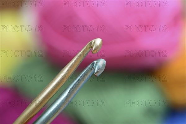 Two crochet hooks on a background of colorful wool