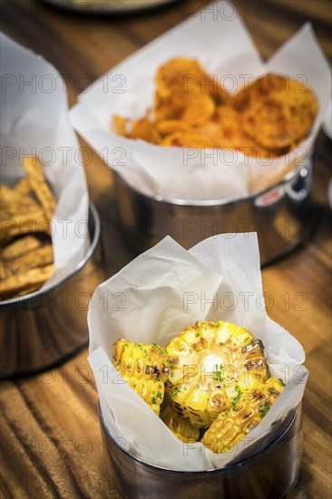 Rustic grilled sweetcorn and other simple snack food on table