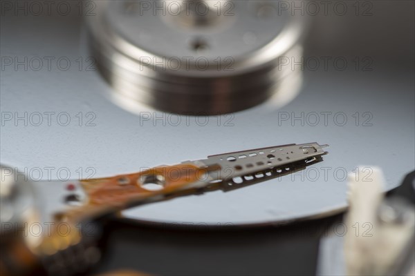 Computer hard drive, opened, read/write head on the storage disc. Symbol image