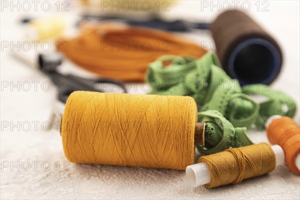 Sewing accessories: scissors, thread, thimbles, braid on gray concrete background. Side view, close up, selective focus