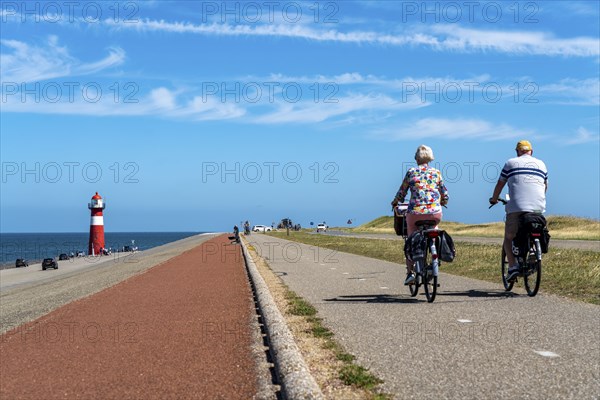 North Sea dyke near Westkapelle, Westkapelle Laag lighthouse, cyclists on the Zeeuwse Wind Route cycle path, province of Zeeland, Walcheren peninsula, Netherlands