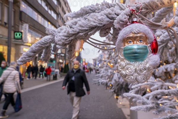 Symbolic picture Christmas in the Corona crisis, Father Christmas figure, Christmas tree decoration, with mouth-nose mask, everyday mask, in a pedestrian zone, shopping street