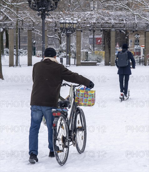 Winter in the city, cyclist pushes his bike over the closed snow cover in front of the opera, e-scooter driver, Frankfurt am Main, Hesse, Germany, Europe