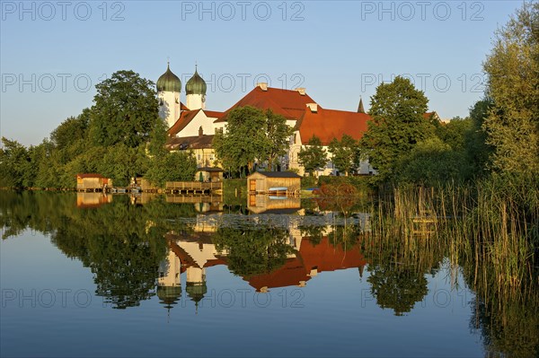 Romanesque Benedictine Abbey Seeon Monastery, monastery church St. Lambert with reflection in the monastery lake, calm smooth water in the evening light at sunset, Seeon-Seebruck, Chiemgau, Upper Bavaria, Bavaria, Germany, Europe