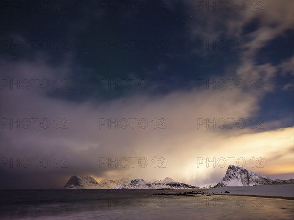 Snow-capped mountains on the coast at night, starry sky and clouds, Vestvagoy Island, Lofoten, Norway, Europe