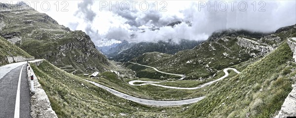 Panorama photo with HDR effect of winding pass road to Alpine pass Colle del Col de Nivolet, low clouds in the background, Gran Paradiso National Park, Ceresole Reale, Piedmont, Italy, Europe