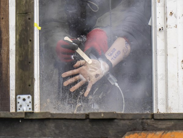 2nd day of the eviction of the hamlet Lützerath, by the police, of tree houses and huts, activist has glued herself to the glass pane of a window, from the inside, police removes the glue, at the opencast lignite mine Garzweiler 2, Erkelenz, North Rhine-Westphalia, Germany, Europe