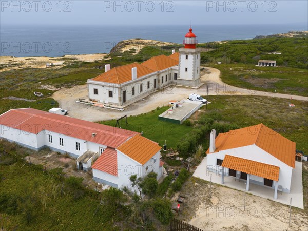 Aerial view of a lighthouse and neighbouring buildings on the coastline, with orange roofs, Farol do Cabo Sardão, Sardao, Ponta do Cavaleiro, Odemira, Alentejo, Portugal, Europe