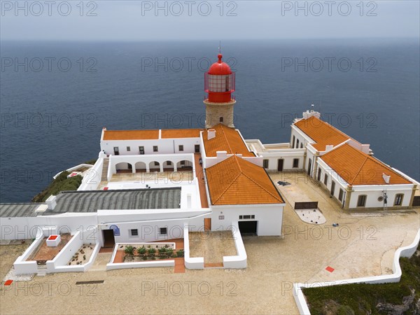 Close-up of a red lighthouse with several white buildings and a courtyard surrounded by the ocean, aerial view, lighthouse, Cabo de São Vicente, Cape St Vincent, Cape St Vincent, Sagres, Portugal, Europe