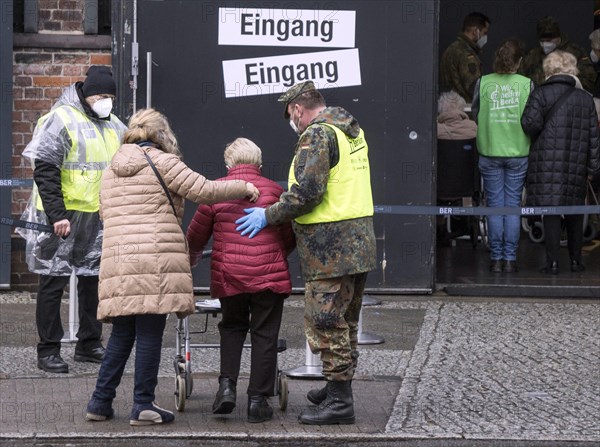 A Bundeswehr soldier helps an elderly woman arriving at the vaccination centre in the Arena in Treptow, Berlin, 09.02.2021