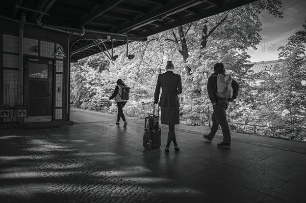 Symbolic photo on the subject of working woman. A woman in a business outfit stands with a suitcase on a platform waiting for a train. Berlin, 08.05.2024