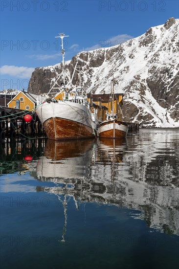 Fishing boats, fishing village with yellow houses in front of snowy mountains, Nusfjord, Flakstadoya or Flakstadøy, Vestvågøya island, Lofoten, Norway, Europe