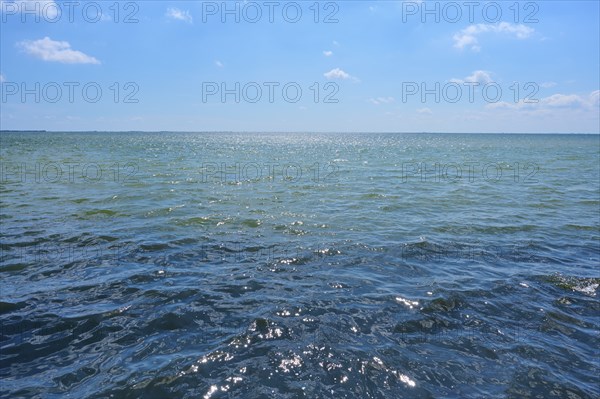 A calm summer's day on the Mediterranean with blue skies and soft clouds, through which the sun's rays shine, Saintes-Maries-de-la-Mer, Camargue, France, Europe