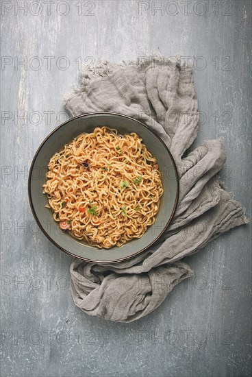 Instant noodles, in a bowl, on a gray table, top view, no people