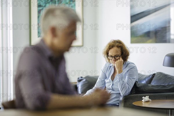 Symbolic photo on the subject of problems in a partnership. An older woman and an older man sitting at home. Berlin, 13.08.2024