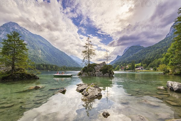 Hintersee with rocks and trees in the foreground, surrounded by mountains after sunset with dramatic cloudy sky, pedal boat, Ramsau, Berchtesgaden National Park, Berchtesgadener Land, Upper Bavaria, Bavaria, Germany, Europe