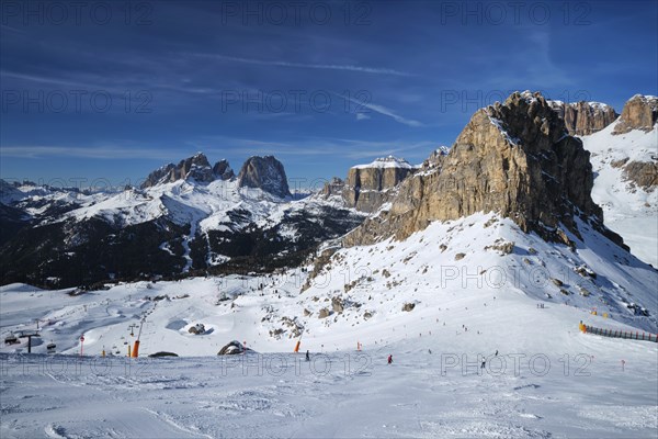 View of a ski resort piste with people skiing in Dolomites in Italy. Ski area Belvedere. Canazei, Italy, Europe