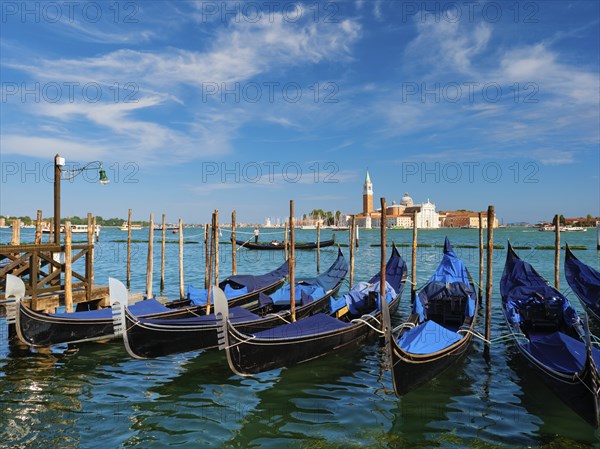 Gondolas and gondolier in lagoon of Venice by Saint Mark (San Marco) square with San Giorgio di Maggiore church in background in Venice, Italy, Europe