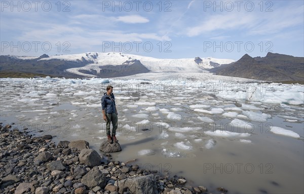 Tourist at glacier lagoon, peak Sveinstindur, ice lagoon Fjallsárlón, ice floes in front of glacier Fjallsjökull, Vatnajökull, Hornafjörður, Iceland, Europe