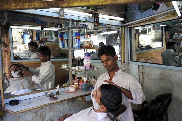 08.12.2011, Mumbai, Maharashtra, India, Asia, A barber shaves a customer in a small men's parlour in the Dharavi slum of Mumbai, Asia