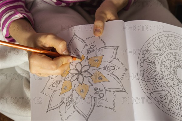 Woman coloring antistress page. Female hand painting mandala. Female painting mandalas to combat stress. Relaxing hobby mental wellbeing and art therapy. Woman paints sketch, meditative process of coloring pages. Self expression by art