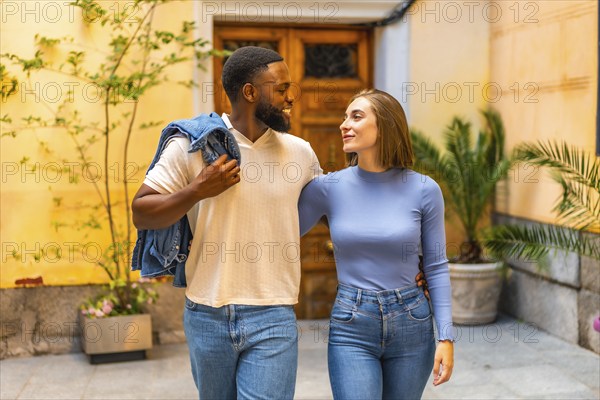 Beauty mixed-race couple with denim casual clothes walking together leaving the house