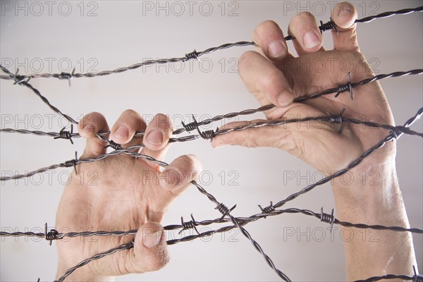 Hands gripping the barbed wire in the sign to run away with the white background